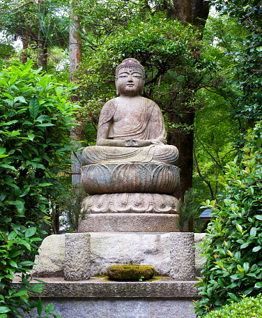 Reproduction of a japanese Goddess. Detail of an old style japanese symbol, this kind of statuary usually appears in temples and cementeries . Trees in the background.