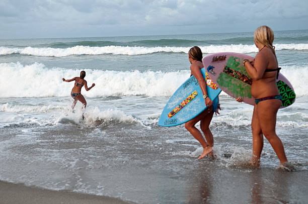 skimboarding на пляже в indialantic, штат флорида - skimboard стоковые фото и изображения