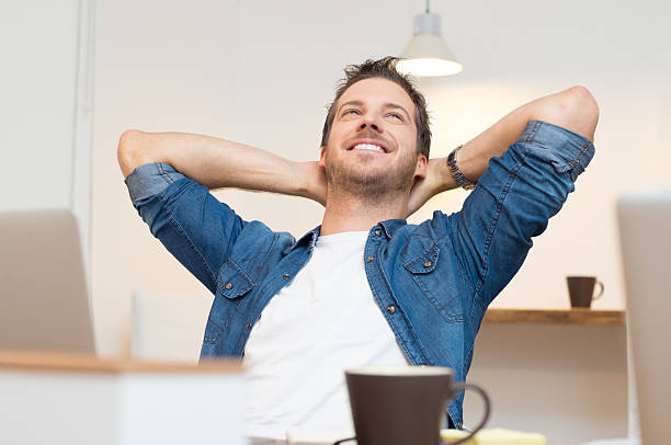 Relaxed young man Young businessman sitting with hands behind head in office serene people stock pictures, royalty-free photos & images