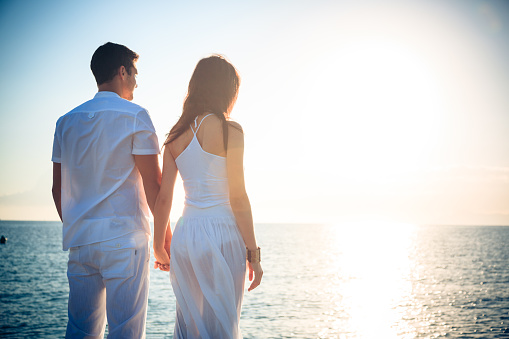 young couple by the sea with the sun rising in the background