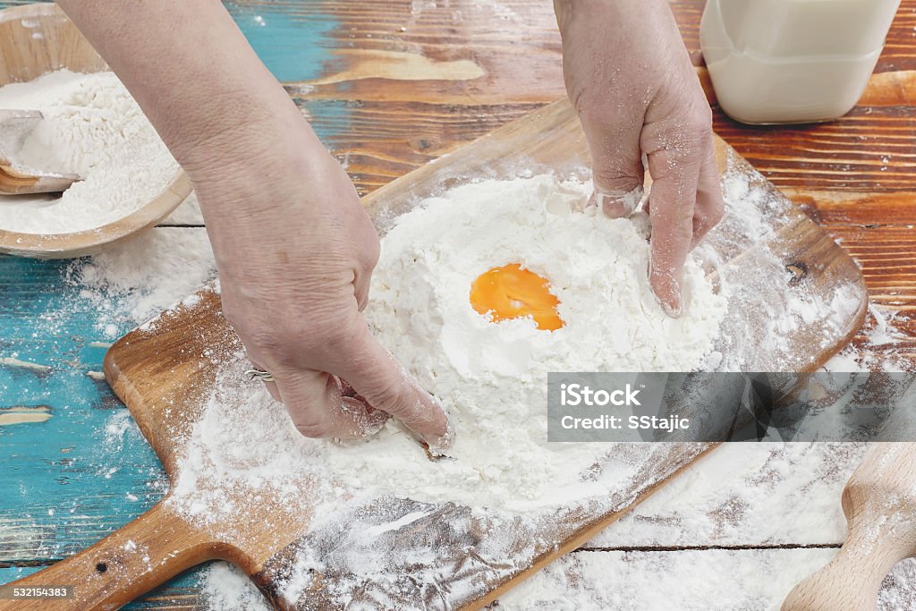 Four and eggs on kitchen counter Hands kneading dough on board - flour and eggs 2015 Stock Photo