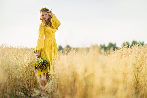Happy young beautiful woman wearing flower garland in fields.