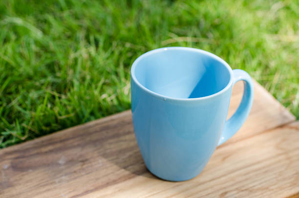 istock Blue mug on wooden board with green grass space. 532168597