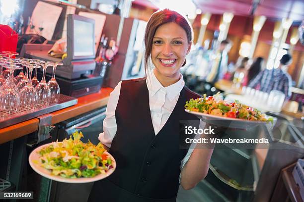 Pretty Barmaid Holding Plates Of Salads Stock Photo - Download Image Now - Waitress, Serving Food and Drinks, Service