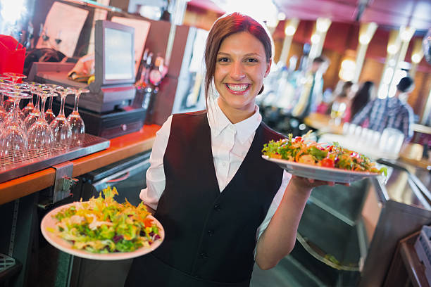 pretty barmaid holding plates of salads - servitör bildbanksfoton och bilder