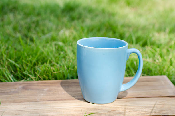 istock Blue mug on wooden board with green grass space. 532169877