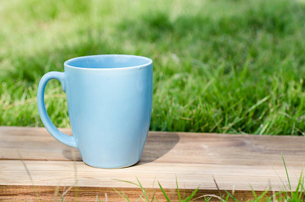 istock Blue mug on wooden board with green grass space. 532169935