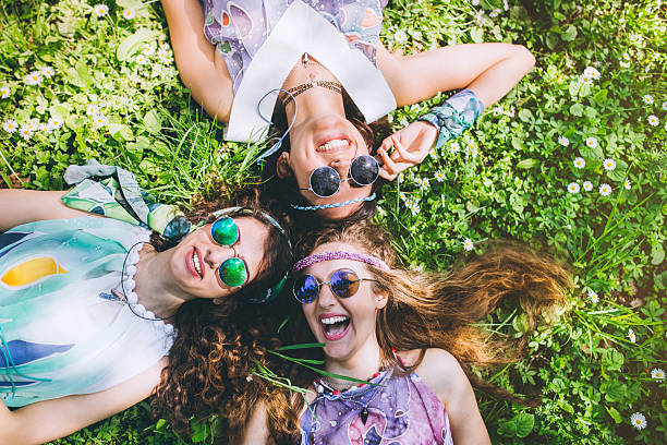 Smiling faces of hippie female friends Beautiful girls of hippie laying on the grass and daisy flowers bohemian fashion stock pictures, royalty-free photos & images