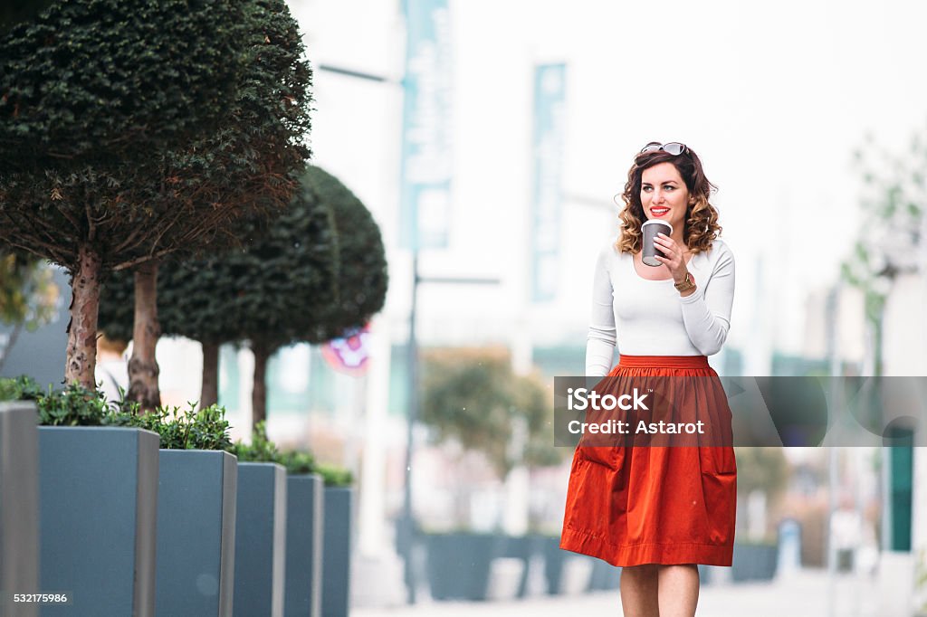 Woman walking down the street and drink coffee to go Young woman walking down the street and drink coffee to go Skirt Stock Photo