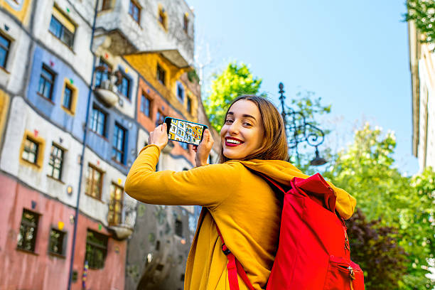 Traveling in Vienna Young female tourist photographing with smart phone Hunderwasser building in Vienna hundertwasser haus in vienna austria stock pictures, royalty-free photos & images