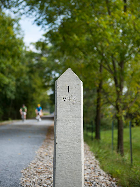 One-mile marker on trail in nature A marker for "mile one" on the Tweetsie Trail in Johnson City, Tennessee. Two unrecognizable cyclists are in the background. tennessee road sign stock pictures, royalty-free photos & images
