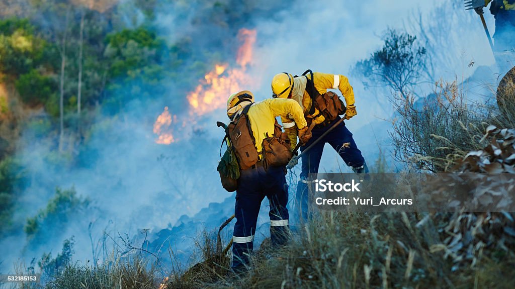 Pushing back the flames Shot of fire fighters combating a wild fire 2015 Stock Photo