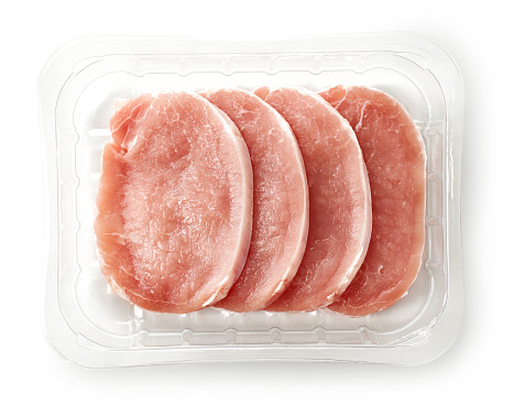 raw pork chops in plastic box isolated on white background, top view