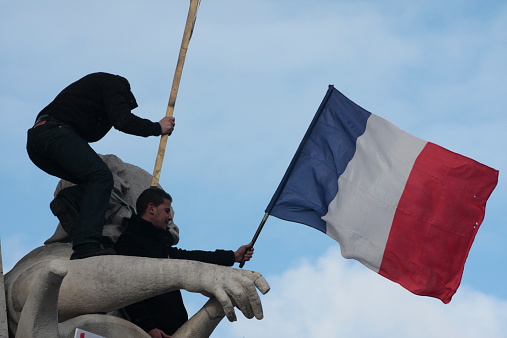 Paris, France - January 11, 2015: Man waving french flag during manifestation on Republic Square in Paris against terrorism and in memory of the attack against satirical newspaper Charlie Hebdo.
