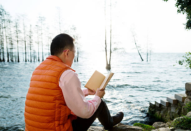 istock Woman reading book by the lake 532187860