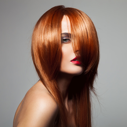 Beauty model with perfect long glossy red hair. Close-up portrait.