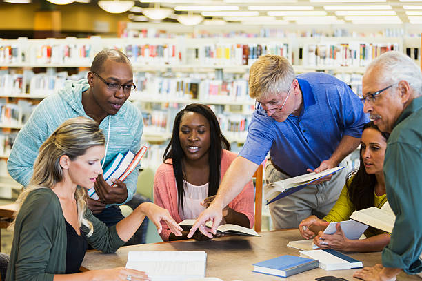 adultes étudiants étudient ensemble dans la bibliothèque - adult student women mature adult library photos et images de collection