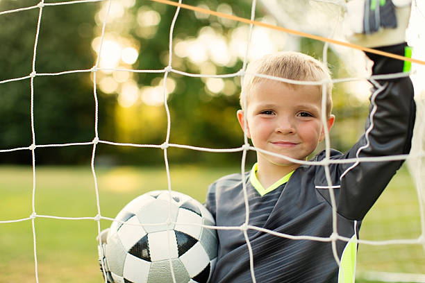 jovem rapaz está segurando bola guarda-redes de futebol - youth league imagens e fotografias de stock