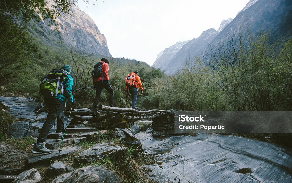 Himalayan trekking Group of trekkers cross the bridge at Annapurna region on Himalayas. Hiking Stock Photo