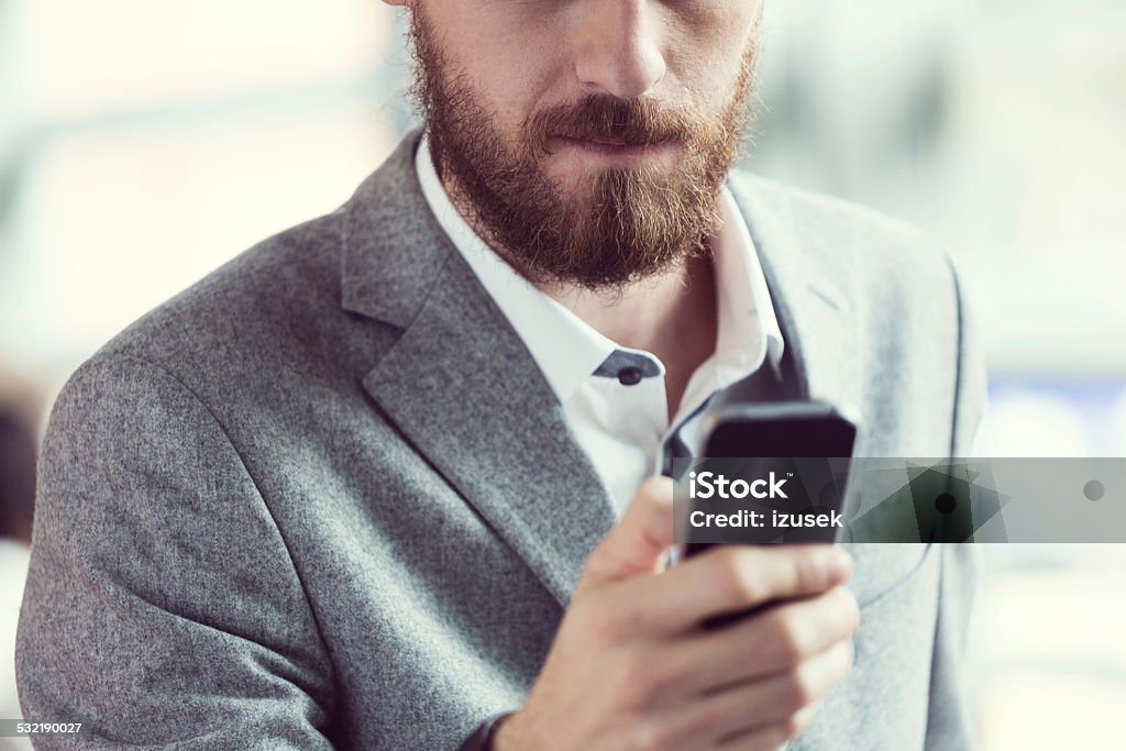 Bearded businessman using smart phone Close up of bearded businessman texting on smart phone. 2015 Stock Photo