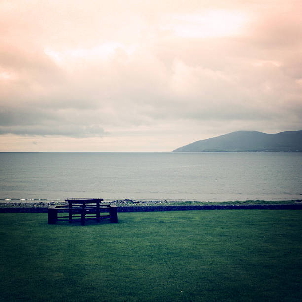 Picnic Table Benches and cloudy seascape in Waterville, County Kerry - vintage effect. Outdoor Table along the Ring of Kerry - retro photo. Ireland.