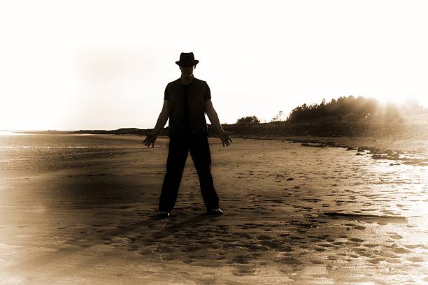Using a metal detector to search for hidden treasure on a beach at sunset