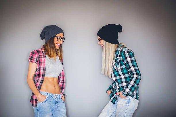 Two hipster friends having fun indoors, sharing secrets