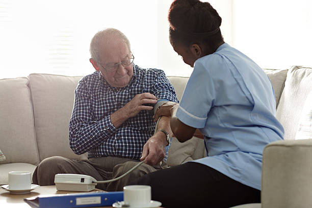 istock Home carer checking patients blood pressure at home 532205313