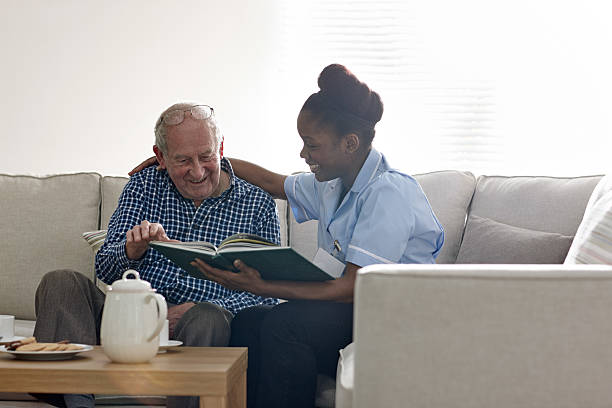 happy senior man carer 読書を一緒に - senior adult relaxation sofa reading ストックフォトと画像