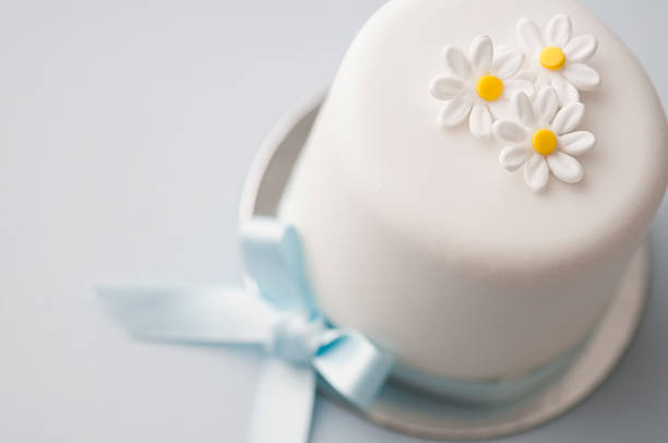 Small iced cake with blue ribbon and icing flowers for a little boys first birthday