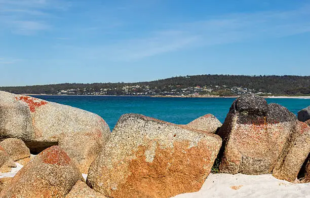 Beautiful rocks at Bay of Fires in Tasmania with town St.Helens in the background