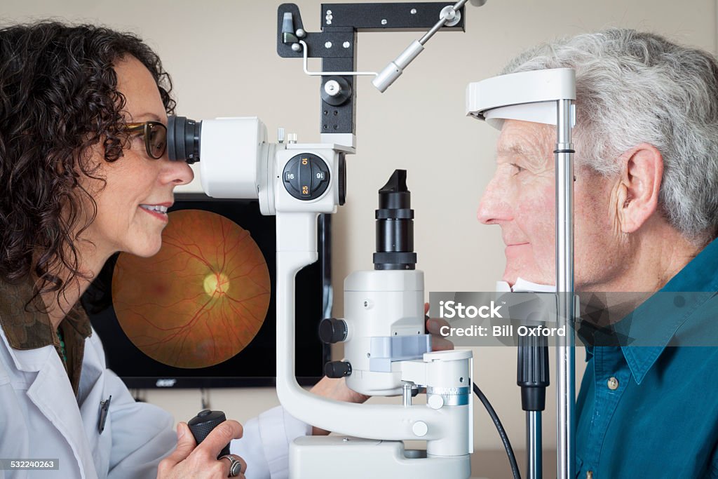 Optometrist with patient Optometrist giving eye exam to senior patient Macular Degeneration Stock Photo