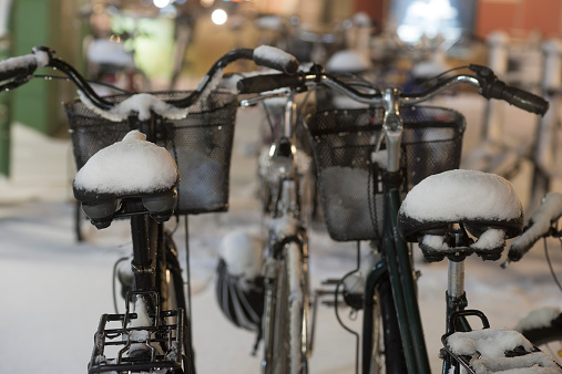 Two parked bikes with snow on seats