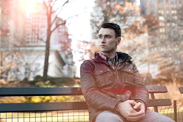 Young Man Sitting on a City Park Bench