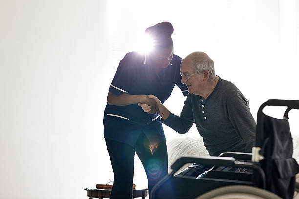 Female nurse helping senior man get up from bed Female nurse helping senior man get up from bed at home personal care aid stock pictures, royalty-free photos & images