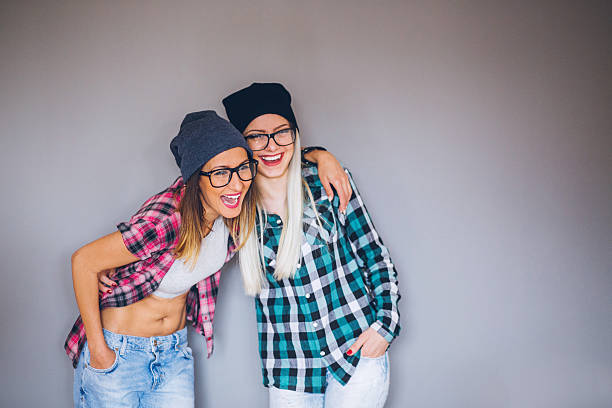 Two hipster friends having fun indoors, sharing secrets