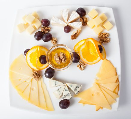 Different cheese cutted on a plate with honey and nuts