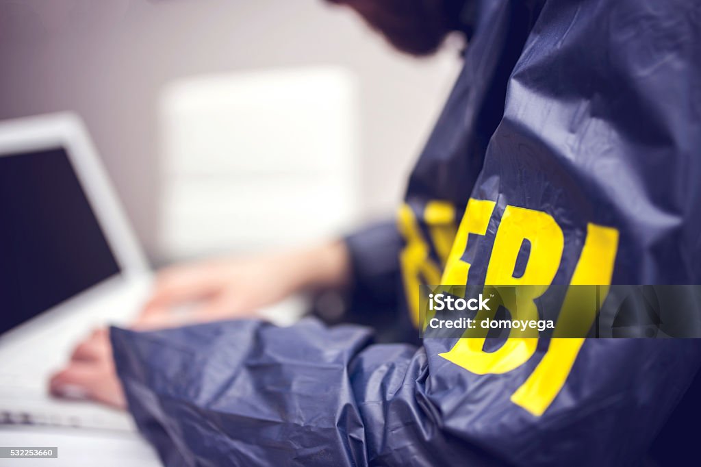 Policeman using laptop in office FBI agent working on his computer in office FBI Stock Photo