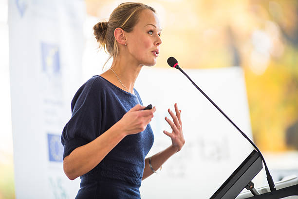 Pretty, young business woman giving a presentation Pretty, young business woman giving a presentation in a conference/meeting setting (shallow DOF; color toned image) announcement stock pictures, royalty-free photos & images