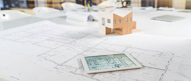Digital tablet, blueprint and model house on a table Digital tablet, blueprint and model house on a table in an architectural bureau. architectural model photos stock pictures, royalty-free photos & images