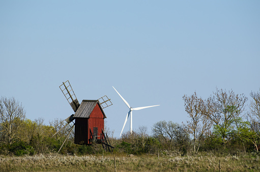 Technical development in form of an old wooden windmill and a new turbine windmill