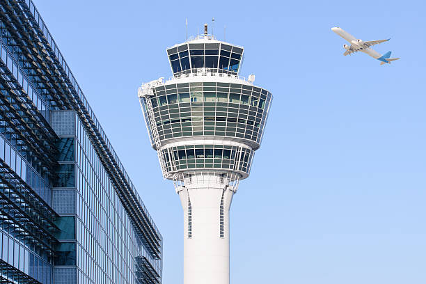Munich international airport control tower and departing taking off Munich international airport control tower and terminal modern buildings with departing taking off plane atc stock pictures, royalty-free photos & images