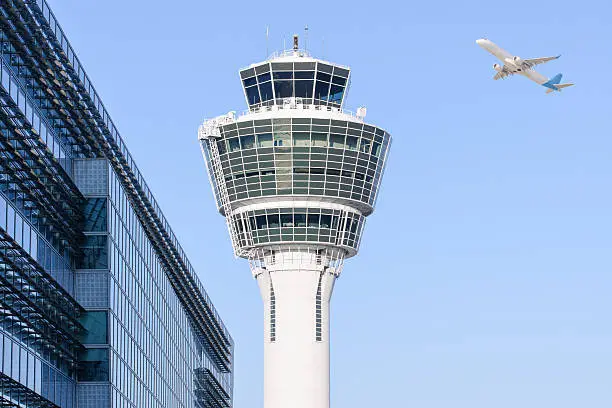 Munich international airport control tower and terminal modern buildings with departing taking off plane