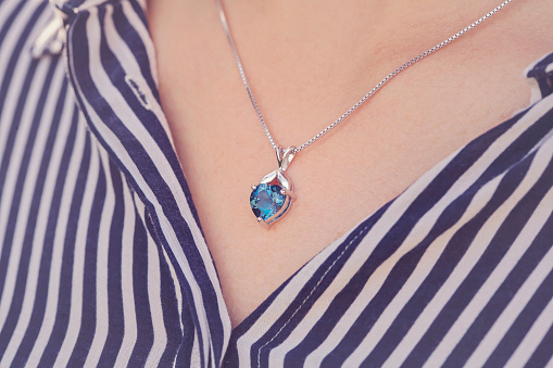 Detal of woman wearing a luxury heart shape sapphire pendant