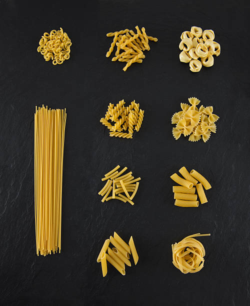 selezione di pasta su sfondo nero ardesia - pasta whole wheat spaghetti raw foto e immagini stock