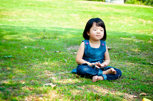 Meditating girl Little asian girl practicing mindfulness meditation outdoor in a park. mindfulness children stock pictures, royalty-free photos & images