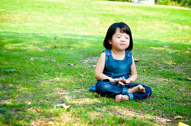Meditating girl Little asian girl practicing mindfulness meditation outdoor in a park. mindfulness kids stock pictures, royalty-free photos & images