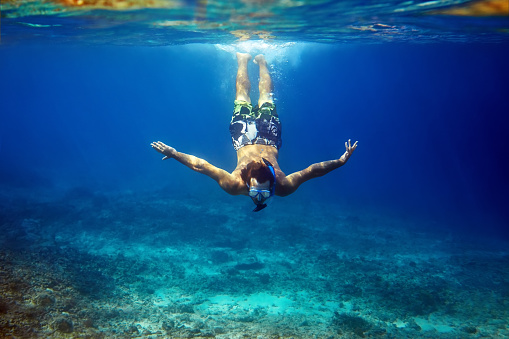 man with mask swimming underwater in tropical sea. vacation concept
