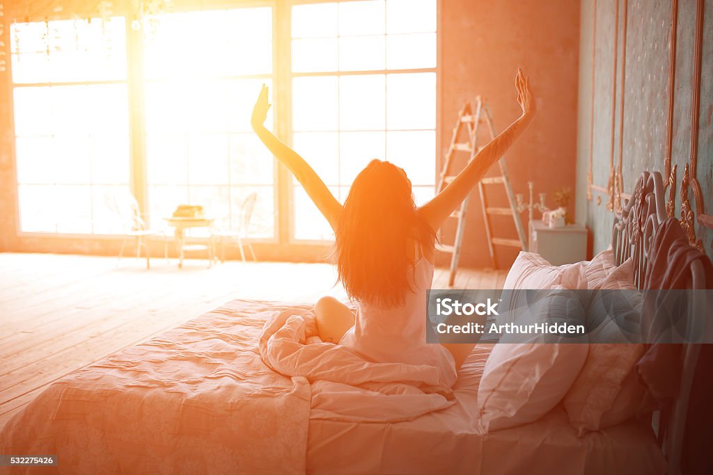 Woman stretching in bed after wake up Woman stretching in bed after wake up, back view Rear View Stock Photo