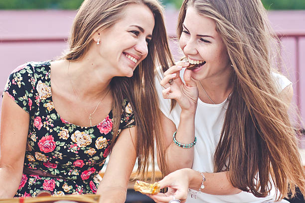 2 つの若い魅力的な女性のお問い合わせと笑い屋外のチョコレート - chocolate candy unhealthy eating eating food and drink ストックフォトと画像